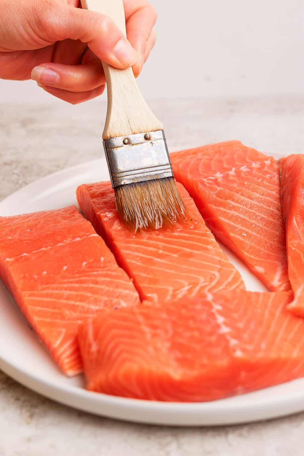 Olive oil being brushed on salmon fillets before they go on the grill.
