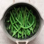 Steamed green beans in a pot with a steamer basket.