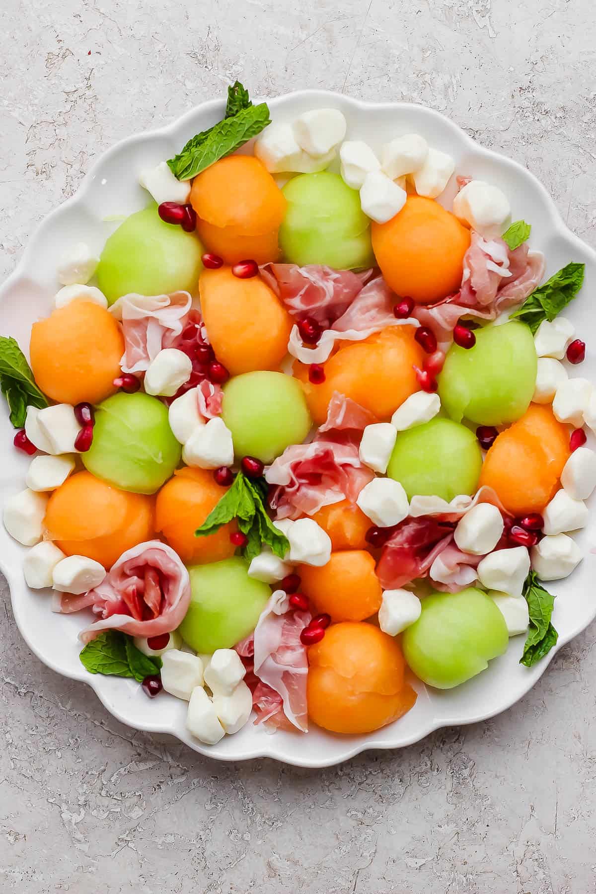 A caprese melon salad on a large platter before the oil, balsamic glaze, salt and pepper are added.