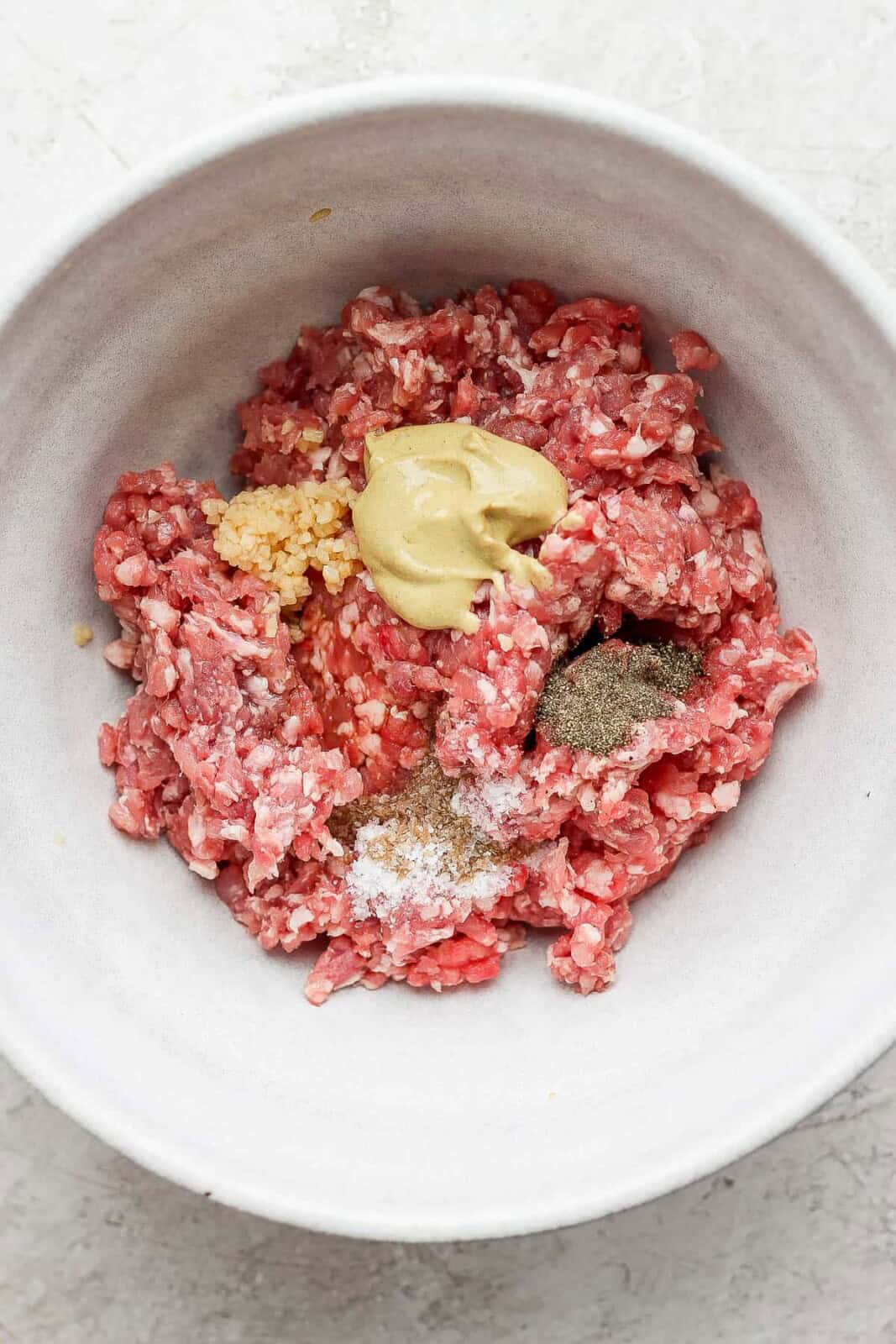 Ingredients for pork burgers separated in a bowl.
