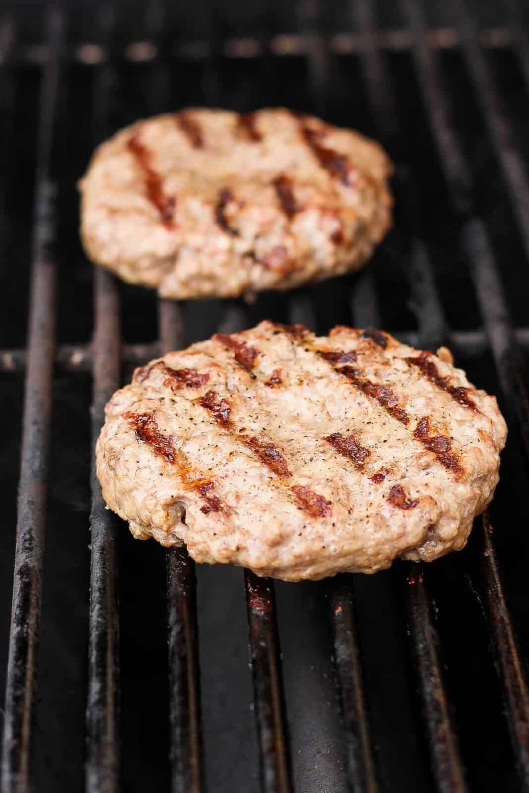 Pork burger patties cooking on the grill.