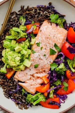 A fully assembled salmon power bowl with a gold fork sticking out the side.