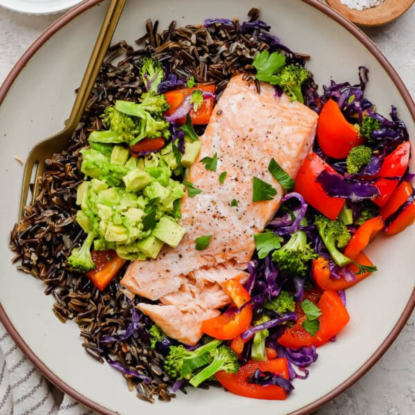 A fully assembled salmon power bowl with a gold fork sticking out the side.