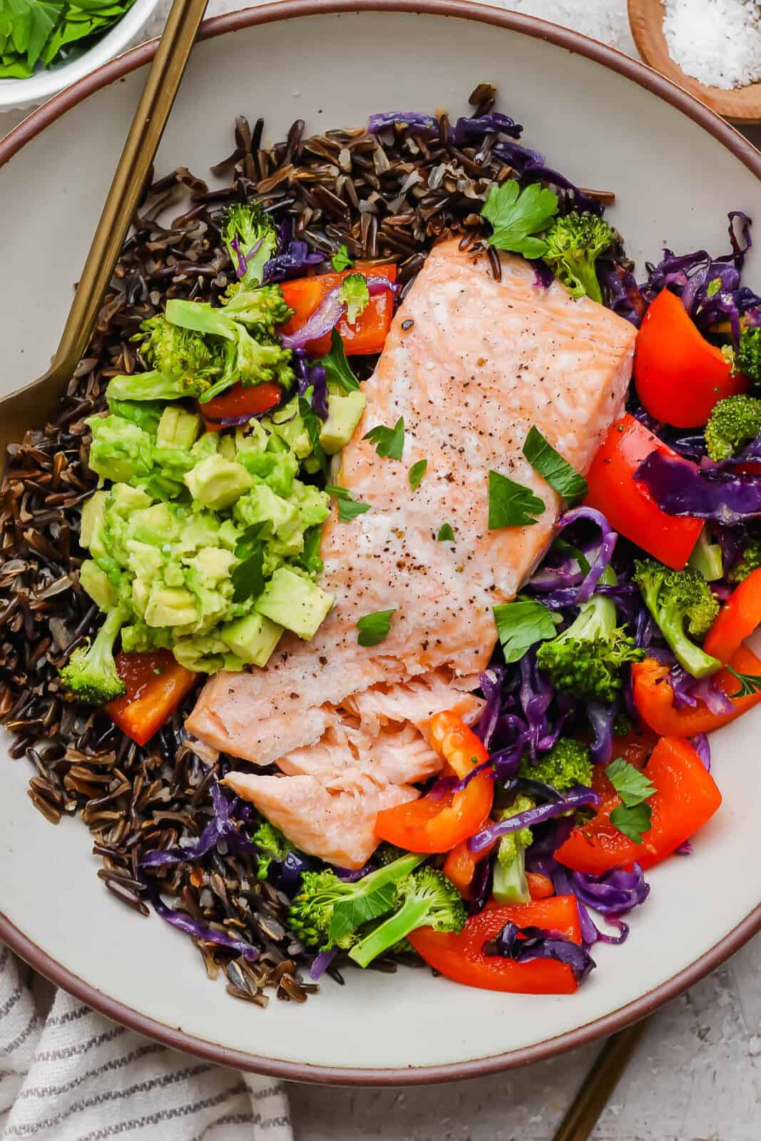 A fully assembled salmon power bowl with a gold fork sticking out the side.