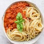A bowl of the best homemade marinara sauce with noodles and fresh basil.