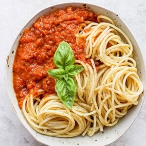 A bowl of the best homemade marinara sauce with noodles and fresh basil.