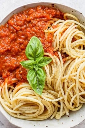 A bowl of the best homemade marinara sauce with noodles and fresh basil.