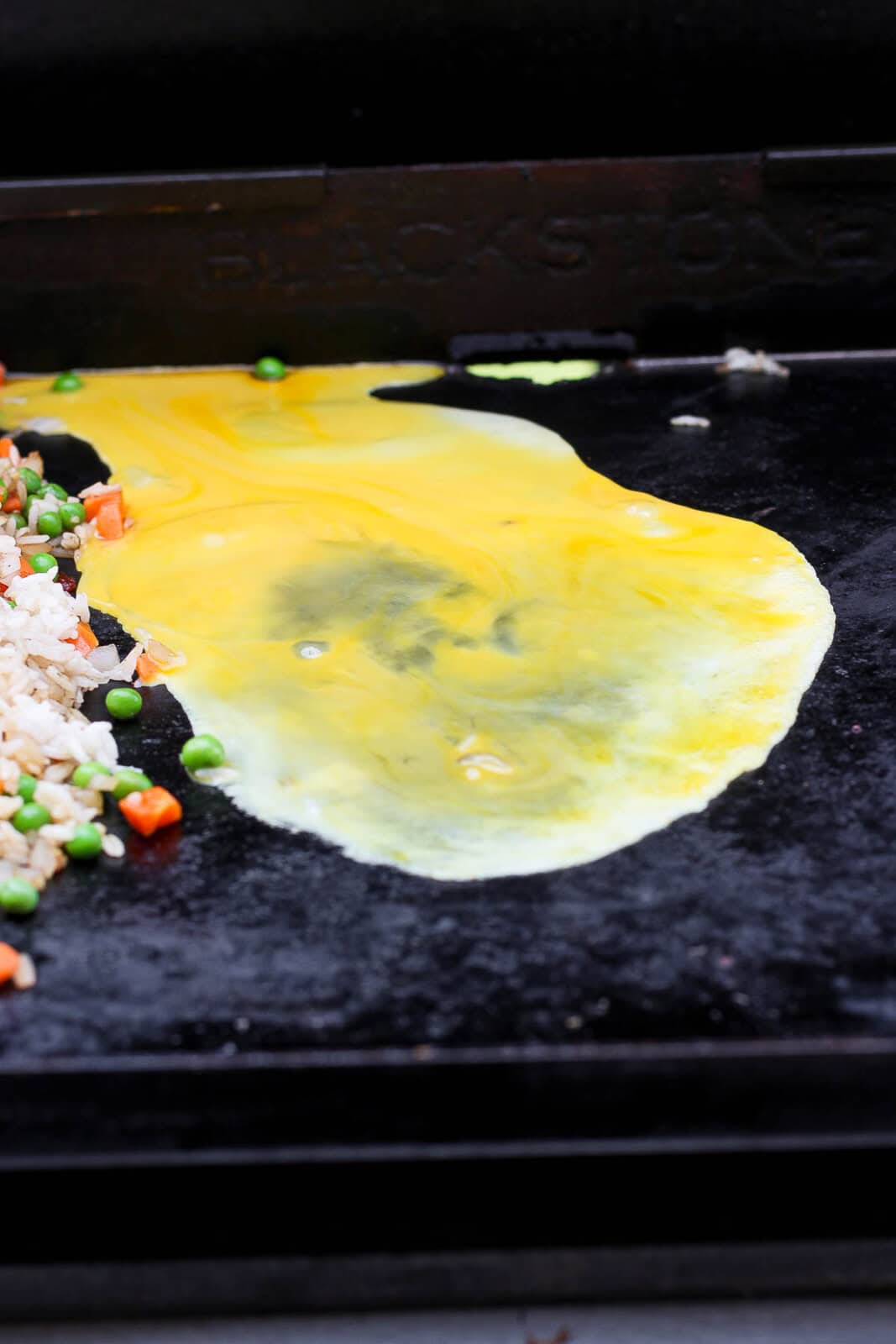 Whisked eggs cooking on the hot griddle for Blackstone shrimp fried rice.