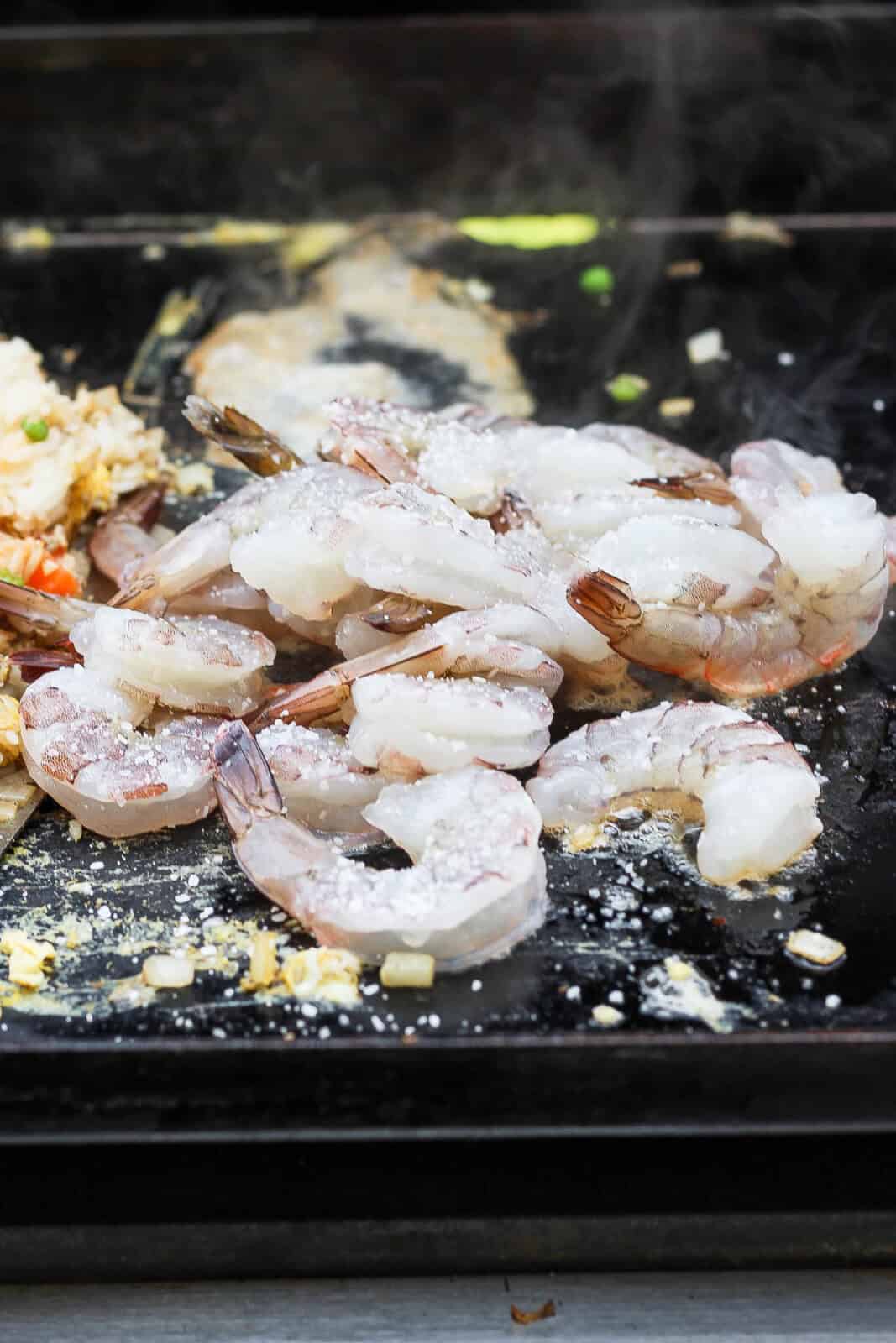 Large shrimp added to the hot cooktop for Blackstone shrimp fried rice.