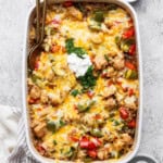 Chicken fajita casserole with rice in a baking dish topped with sour cream and cilantro