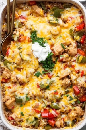 Chicken fajita casserole with rice in a baking dish topped with sour cream and cilantro