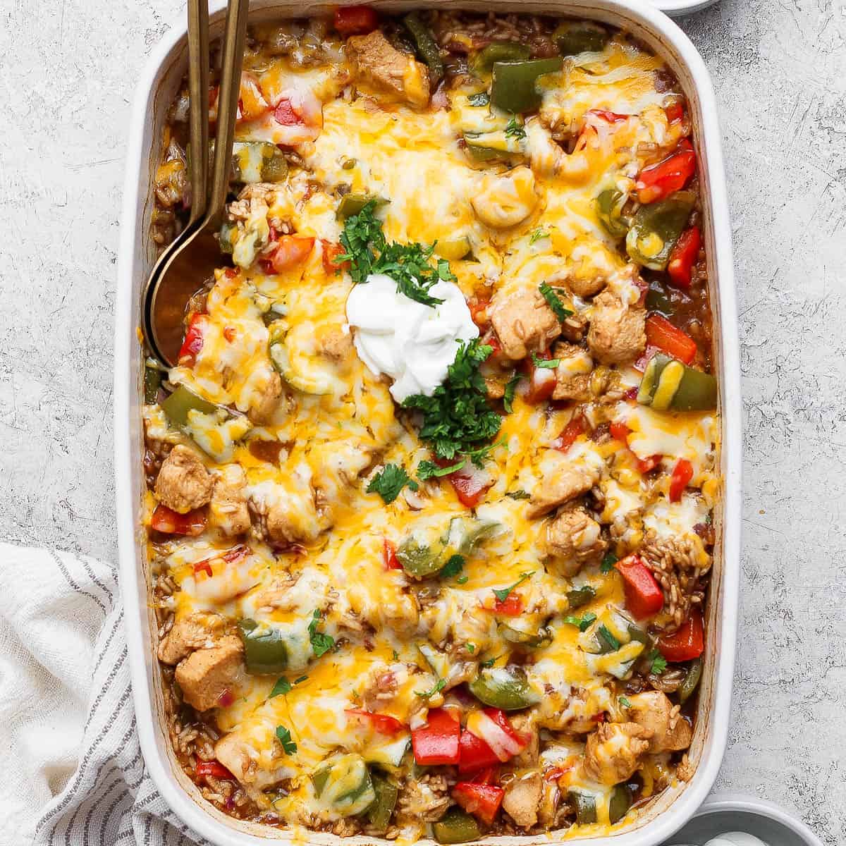 Chicken fajita casserole with rice in a baking dish topped with sour cream and cilantro