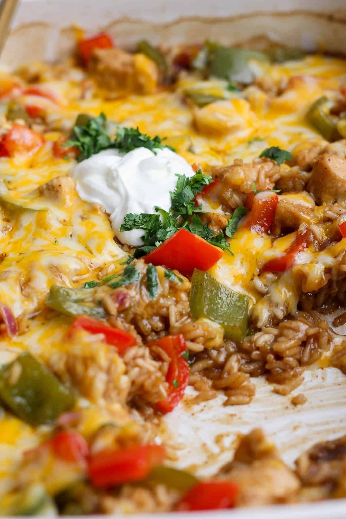 Chicken fajita casserole with rice topped with cilantro and sour cream.