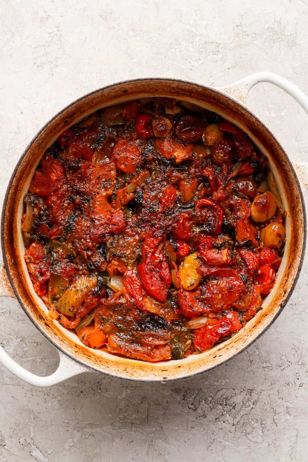 Fully roasted homemade marinara sauce in a white dutch oven.