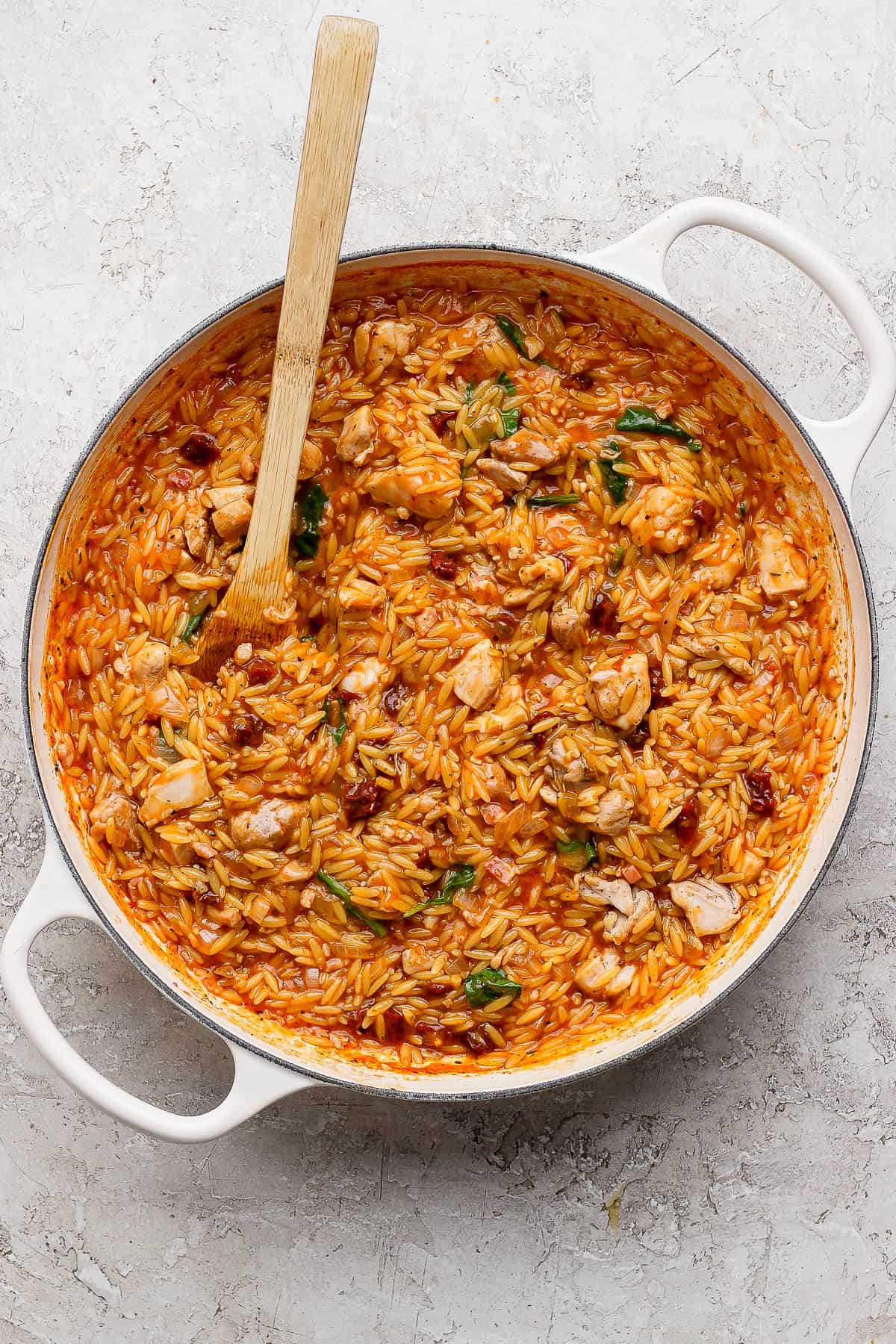 Spinach and parmesan mixed into skillet to make marry me chicken orzo skillet.