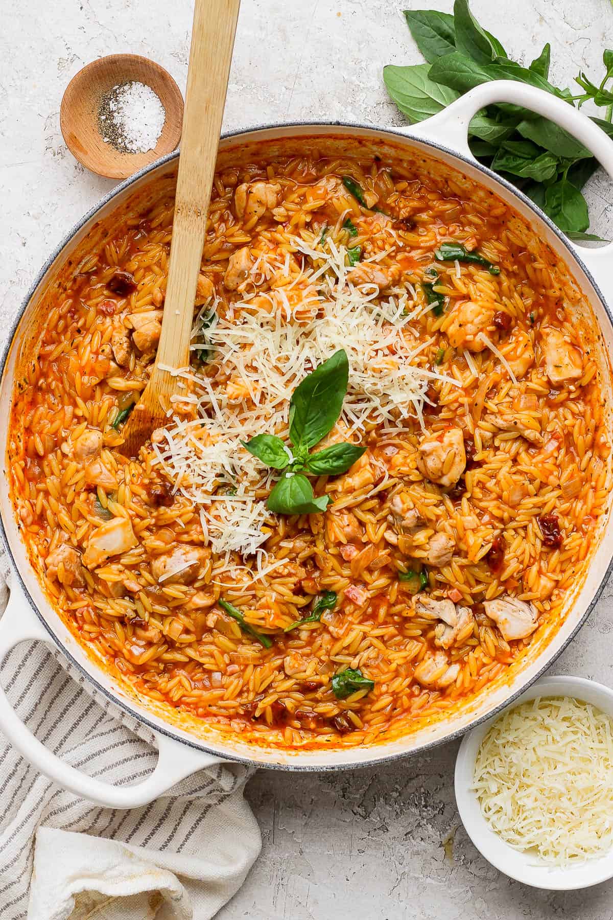 Marry me chicken orzo skillet topped with parmesan cheese and fresh basil.