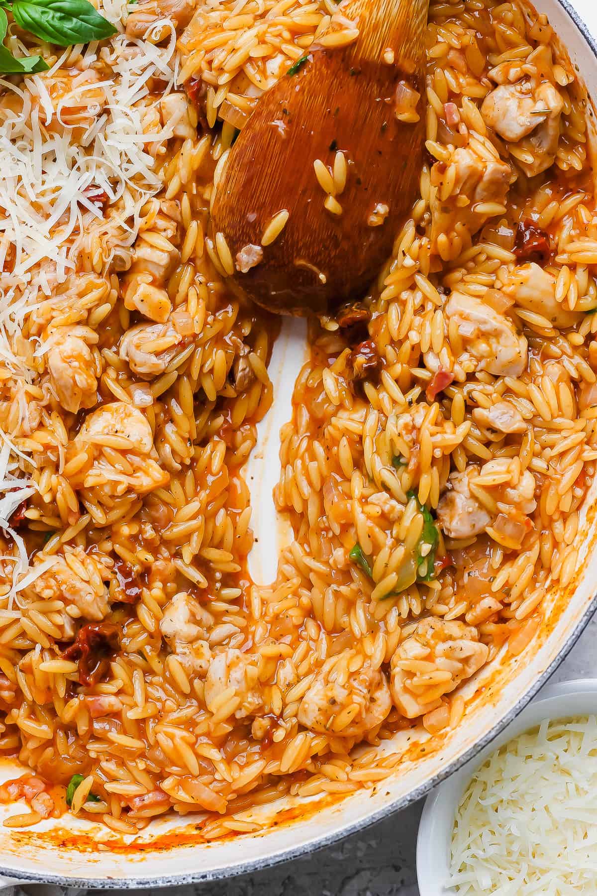 Marry me chicken orzo in a skillet with a wooden spoon.