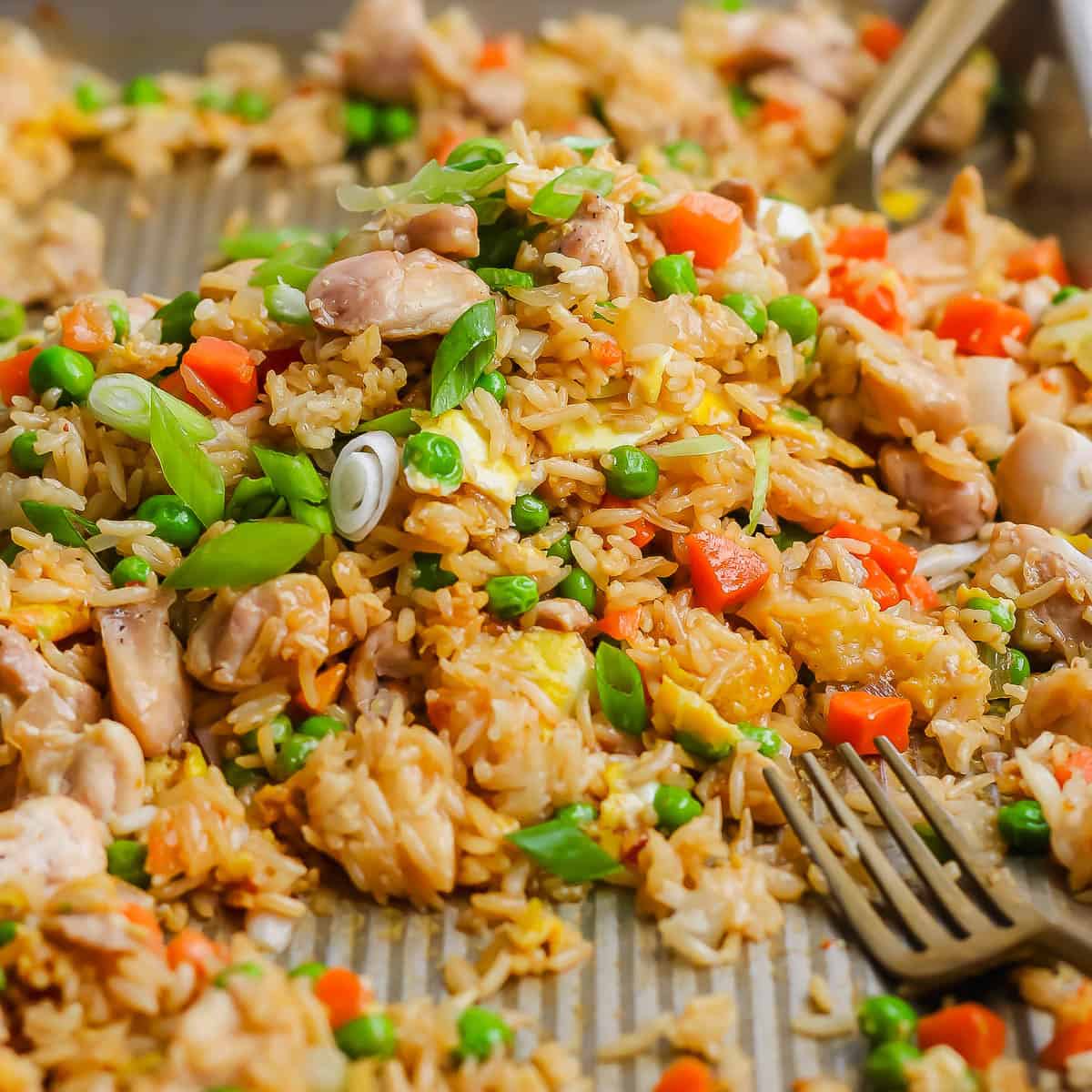 Sheet pan fried rice fully cooked on the sheet pan with two forks.