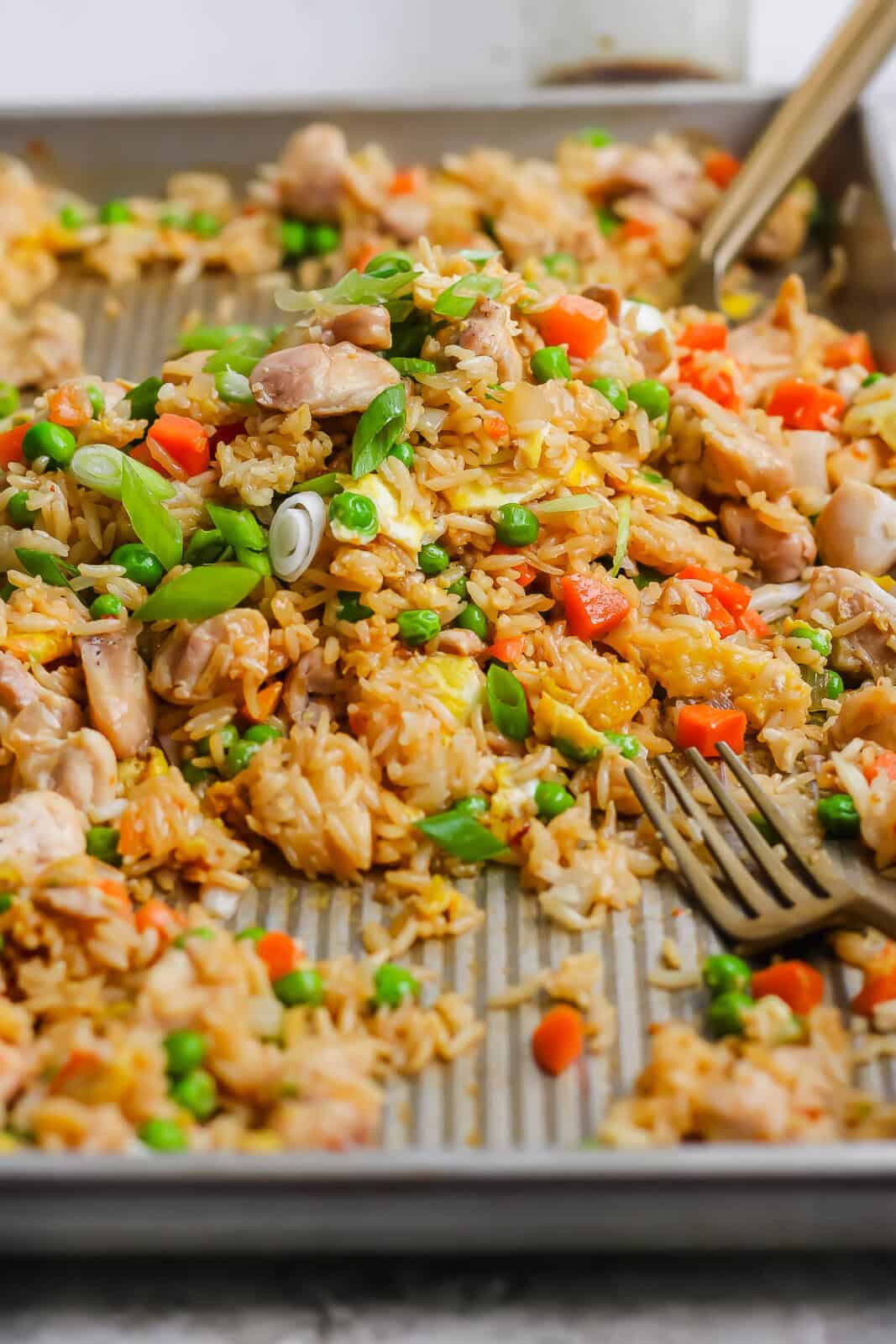 Sheet pan fried rice tossed in the middle of the pan and a gold fork sticking out the side.