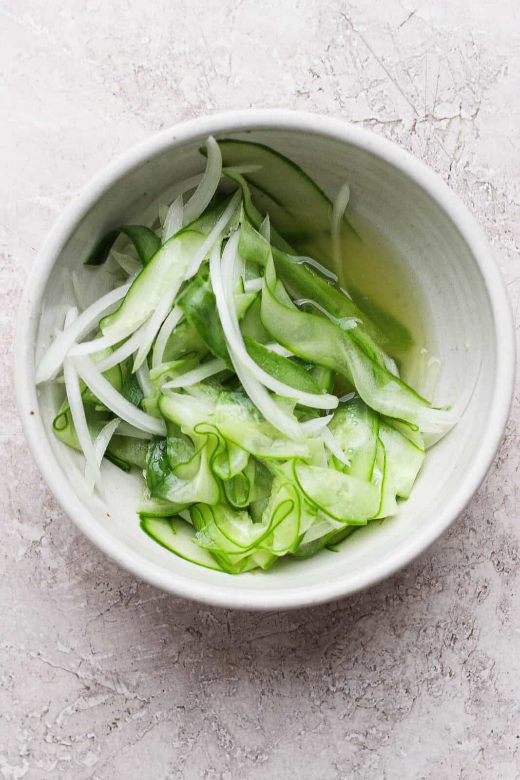 A bowl of marinated cucumbers to serve with Thai chicken skewers.