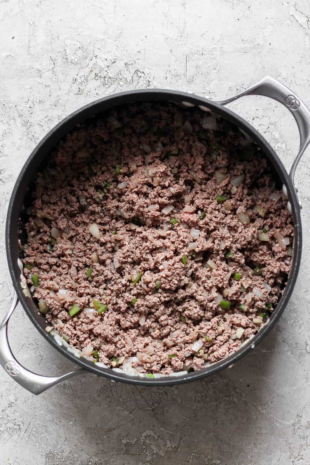 Browned ground bison in a pot with sautéed onion, garlic, and jalapeño to make bison chili.