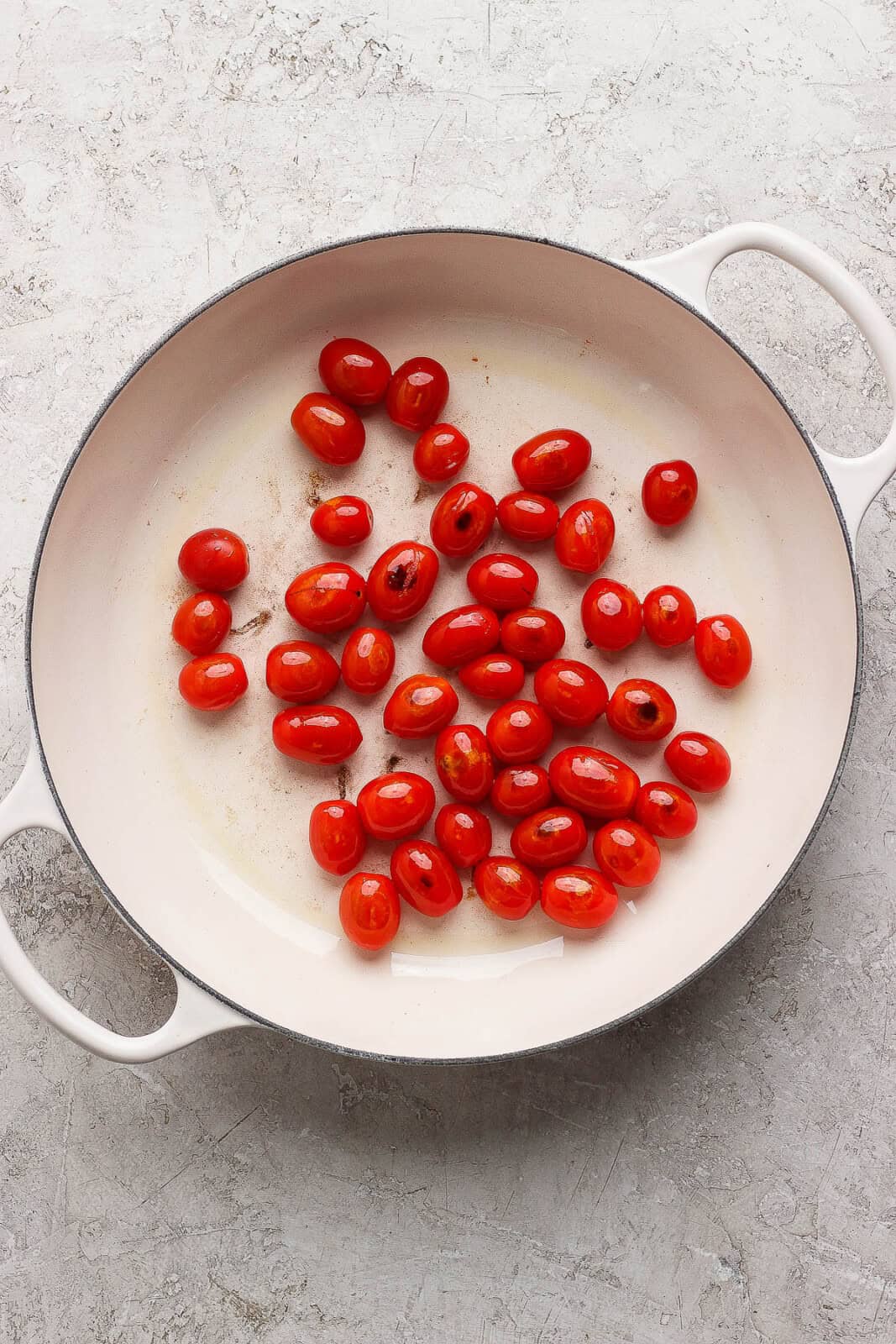 Cherry tomatoes blistering in a pan for making boursin orzo with chicken.