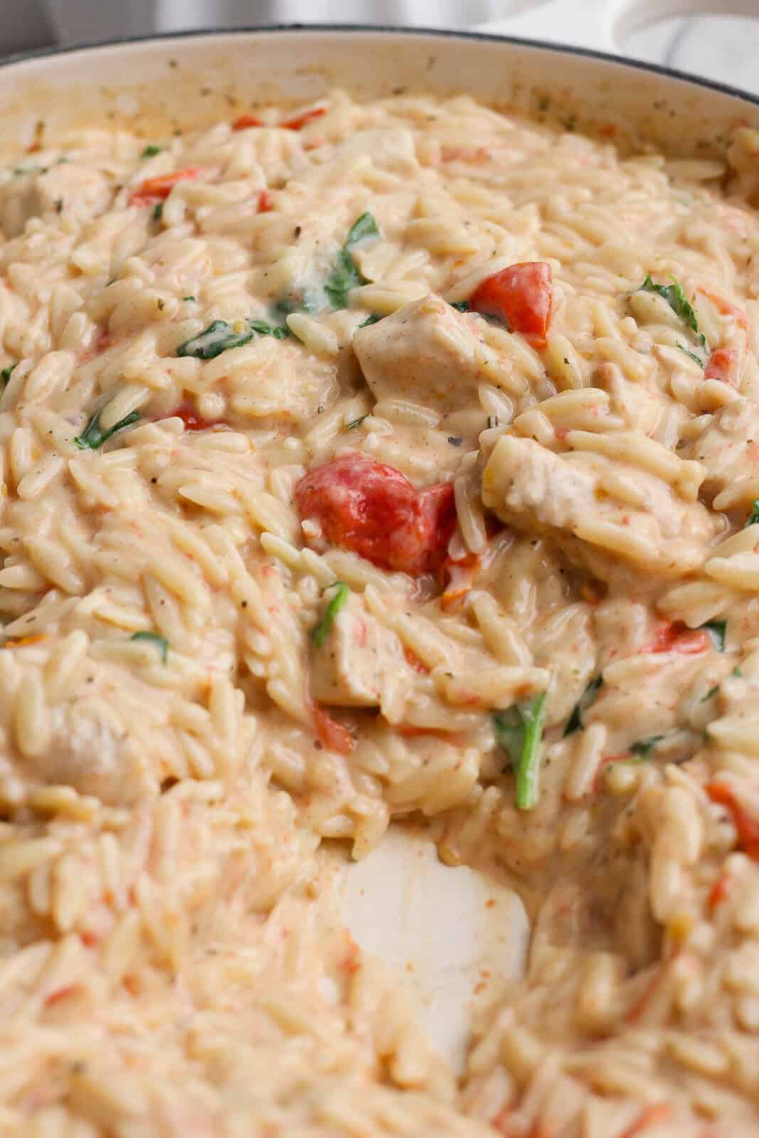 Creamy boursin orzo with chicken in the pan after some has been removed to a dish.