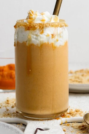 A pumpkin pie shake in a tall glass topped with whipped cream.
