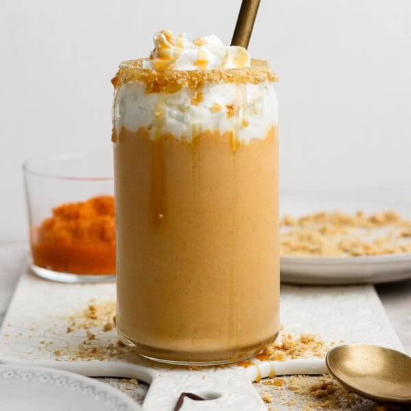 A pumpkin pie shake in a tall glass topped with whipped cream.