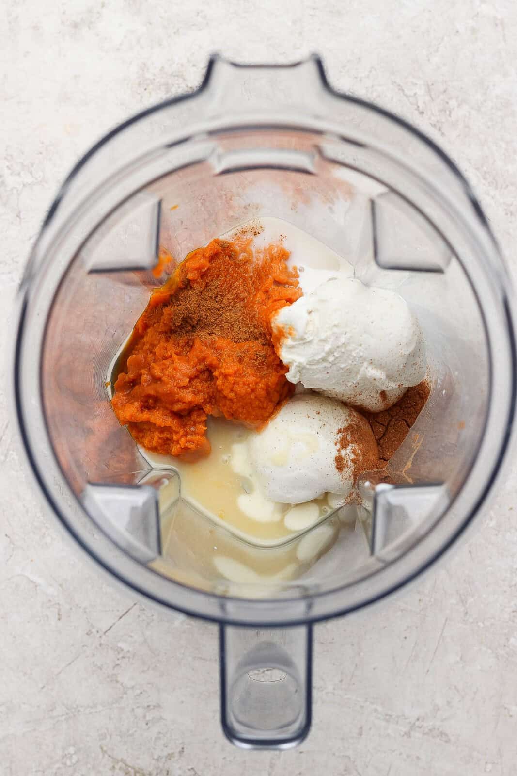 Ingredients for a pumpkin pie shake in a blender before blending.