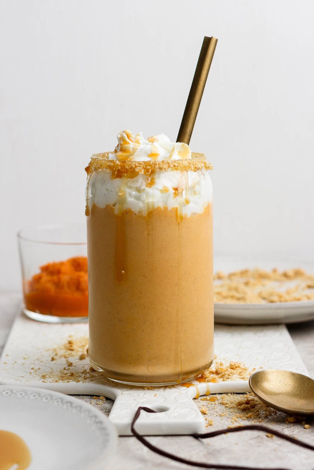 A tall pumpkin pie shake in a glass with a spoon sticking out the top.