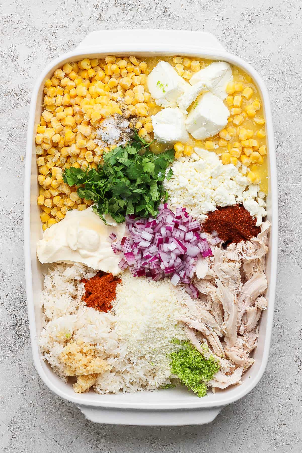 Street corn chicken casserole ingredients separated in a casserole dish.