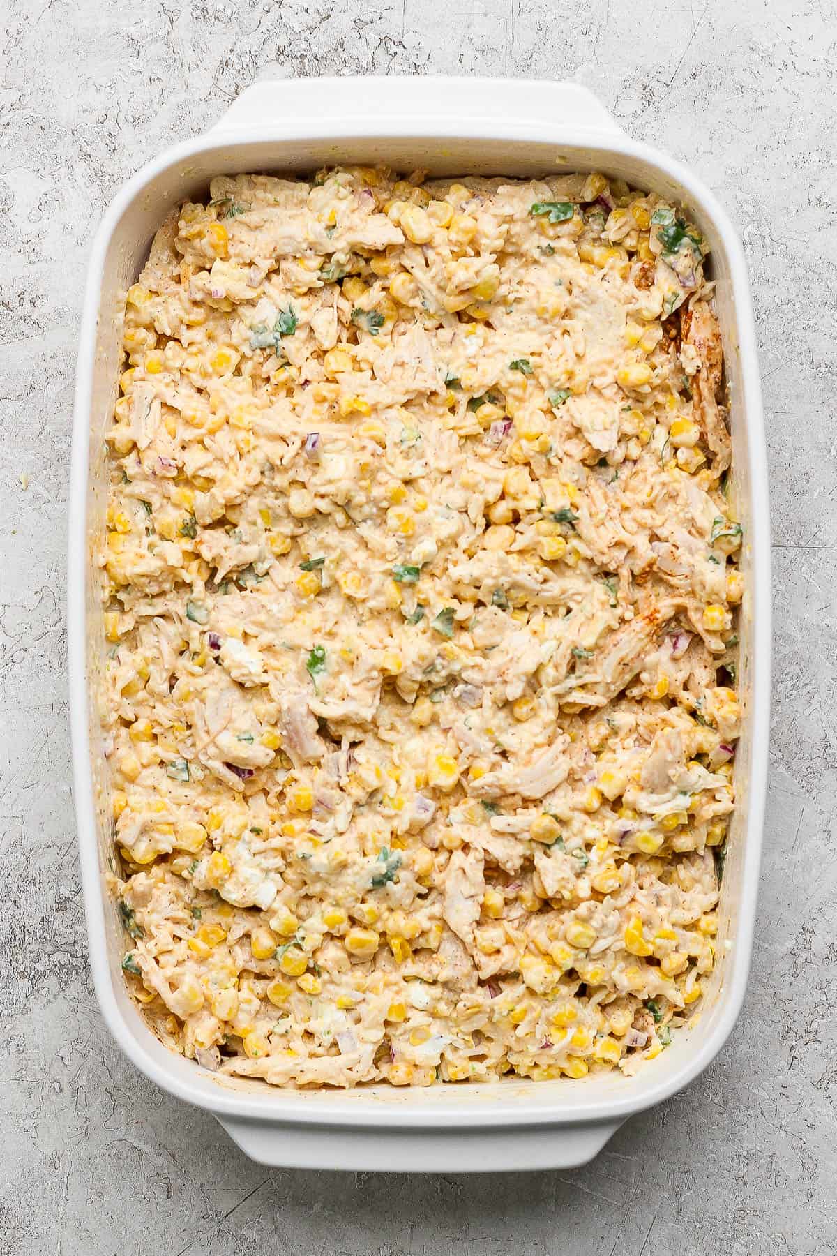 Street corn chicken casserole in a casserole dish before being baked.