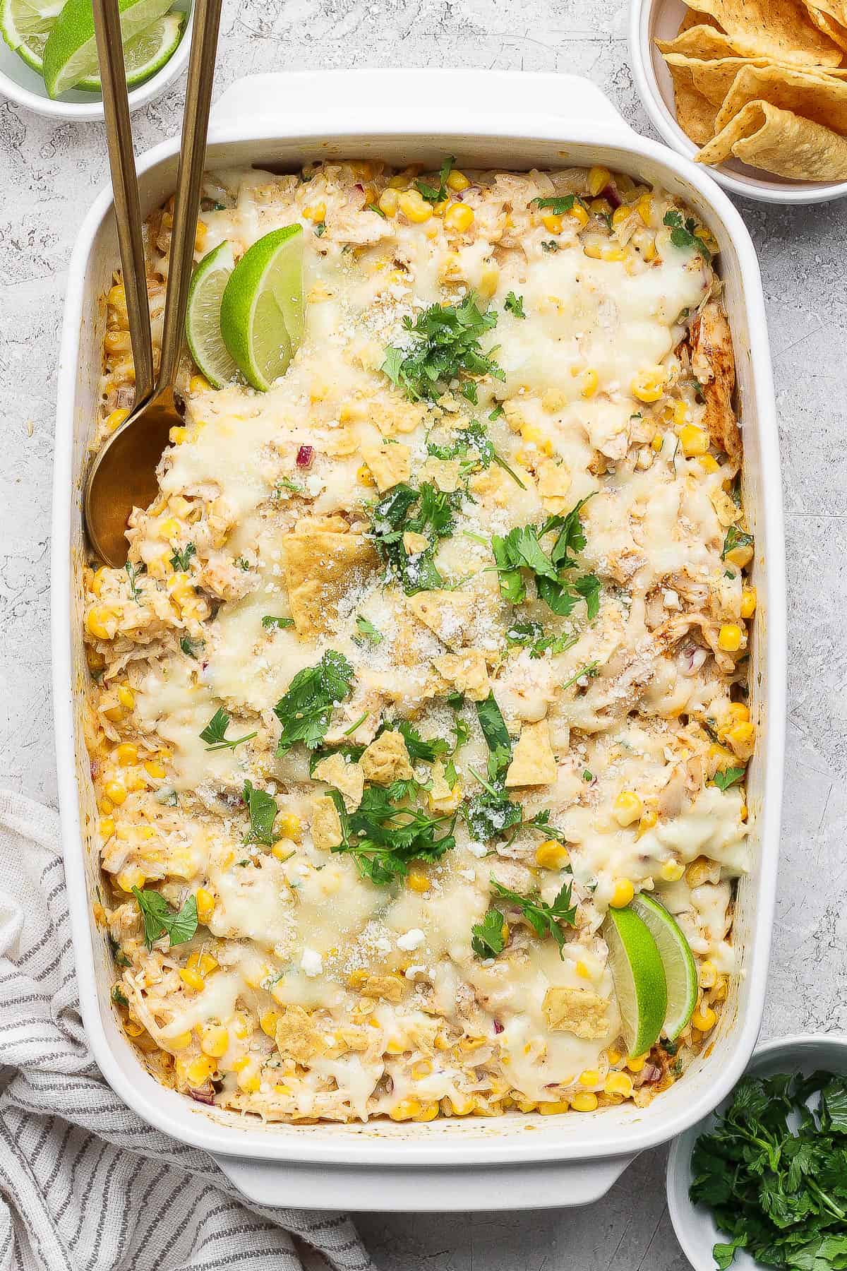 Street corn chicken casserole topped with cojita cheese, chopped cilantro, and lime wedges.