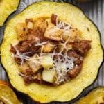 A sausage and apple stuffed acorn squash on a sheet pan after baking.
