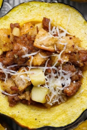 A sausage and apple stuffed acorn squash on a sheet pan after baking.