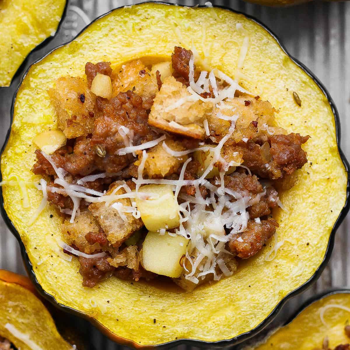 A sausage and apple stuffed acorn squash on a sheet pan after baking.