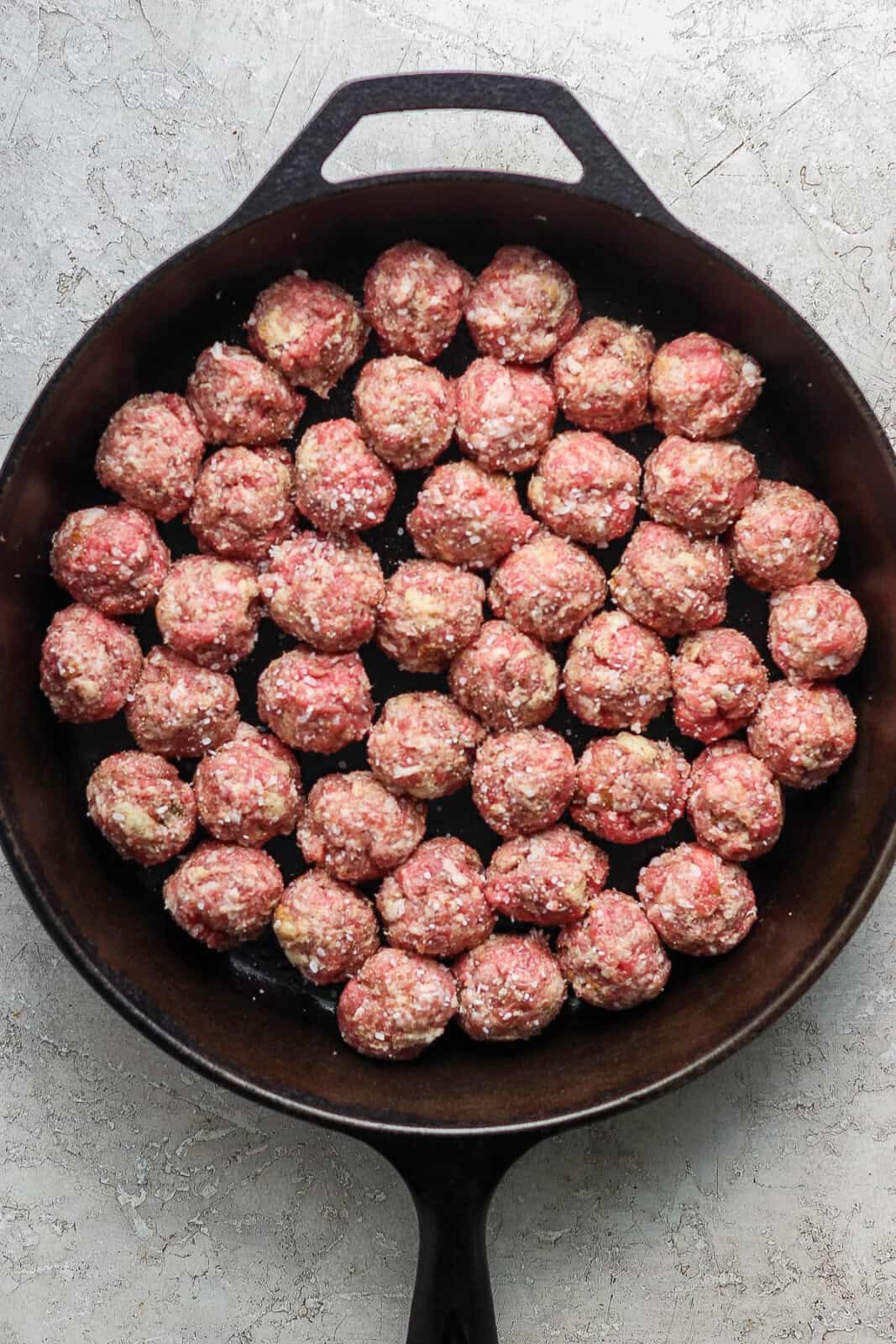 Meatballs for Swedish meatballs in a cast iron skillet before baking.