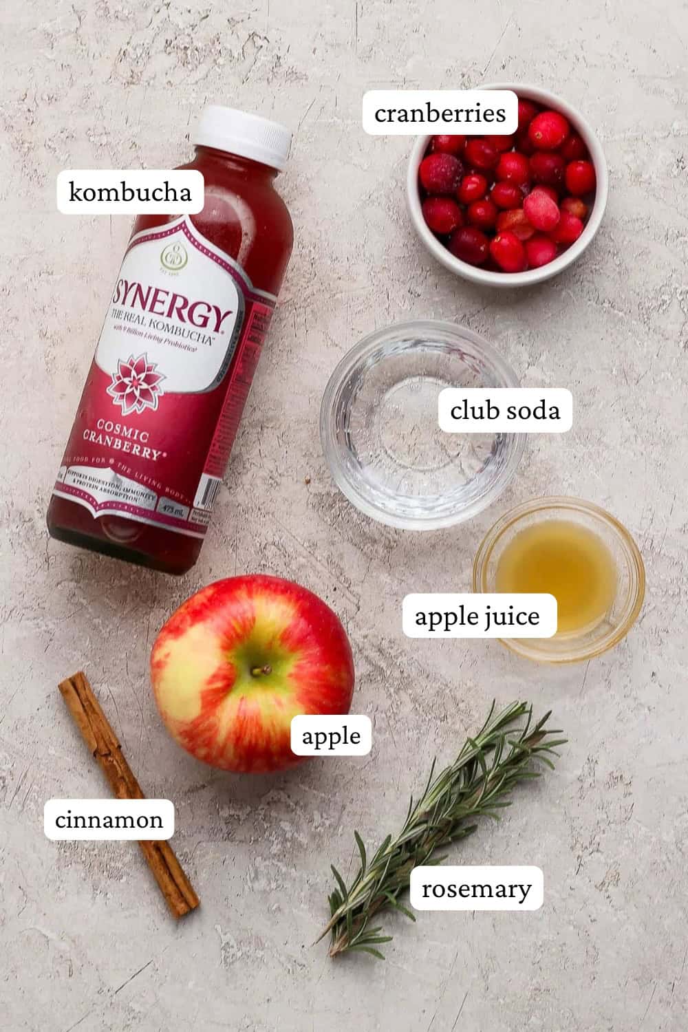 Ingredients for a cranberry kombucha mocktail laid out on the counter with labels.
