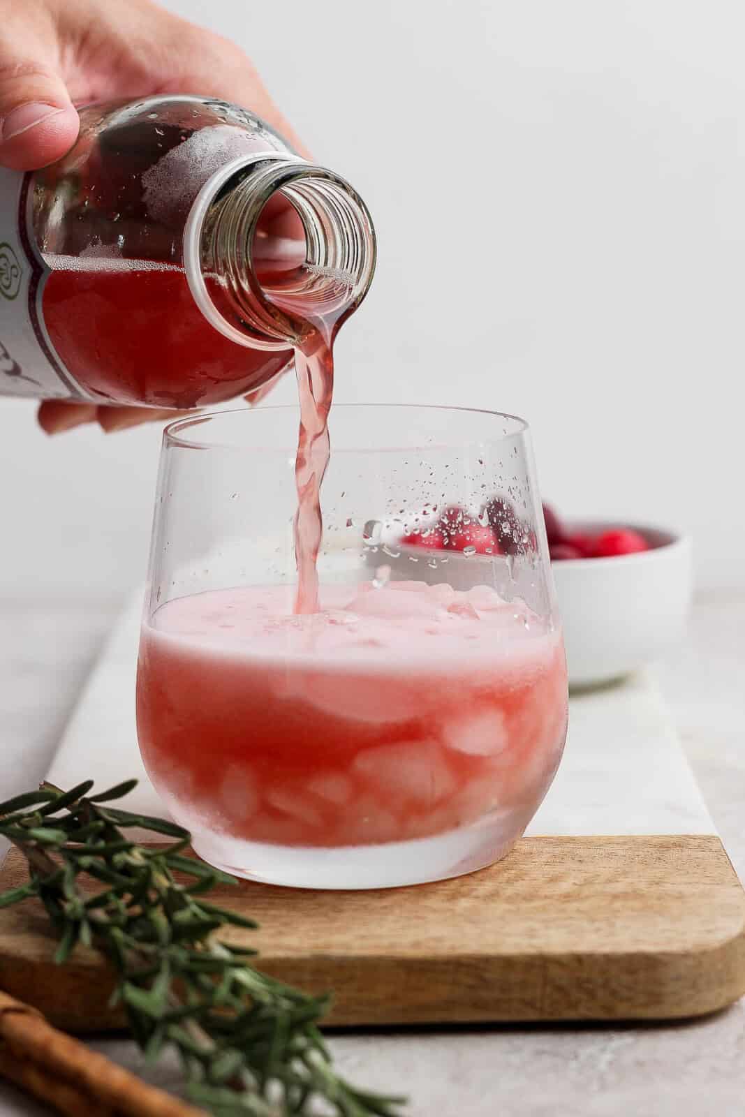 Kombucha being poured over ice for a cranberry kombucha mocktail.