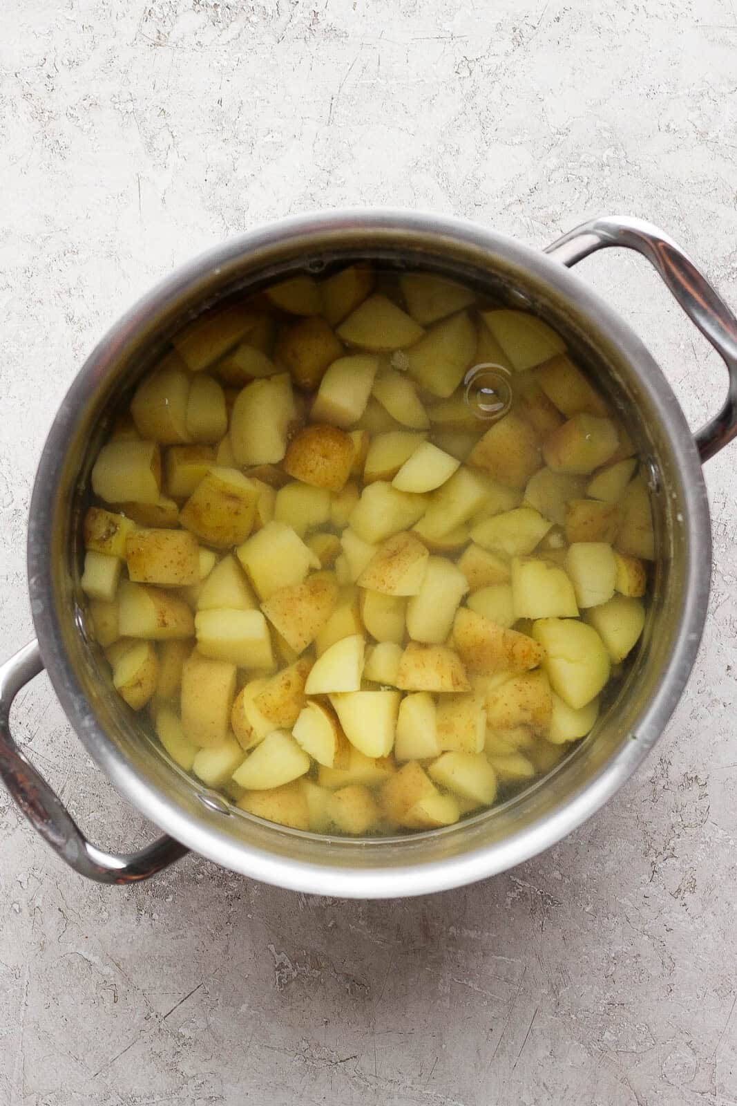 Chunks of Yukon Gold potatoes boiling in a pot of water for horseradish mashed potatoes.