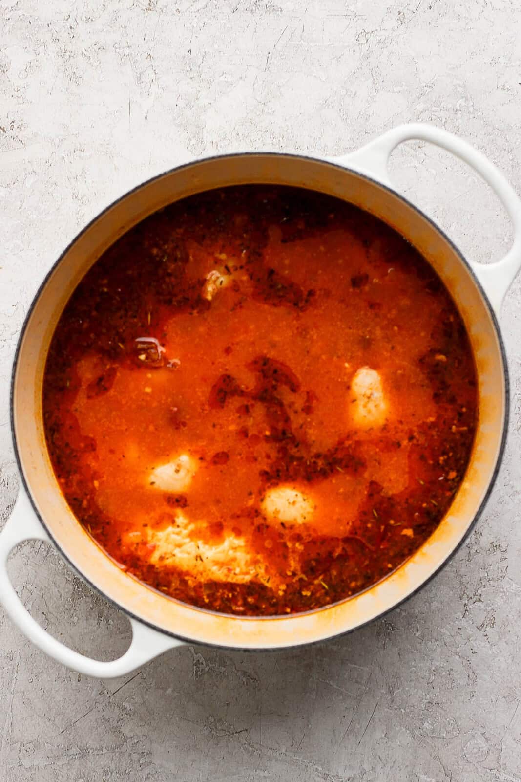 Chicken thighs cooking in a pot of marry me chicken gnocchi soup.