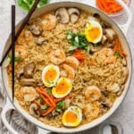 A braising pan full of shrimp ramen with soft boiled eggs cut in half on top.