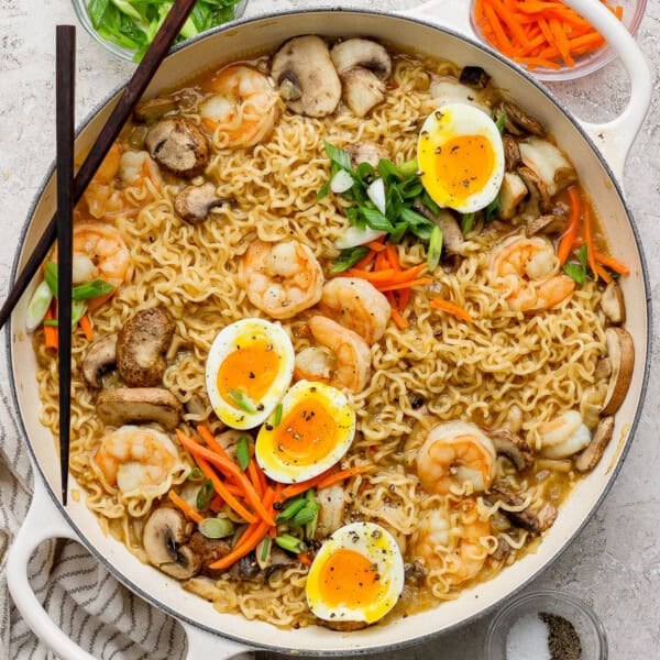 A braising pan full of shrimp ramen with soft boiled eggs cut in half on top.