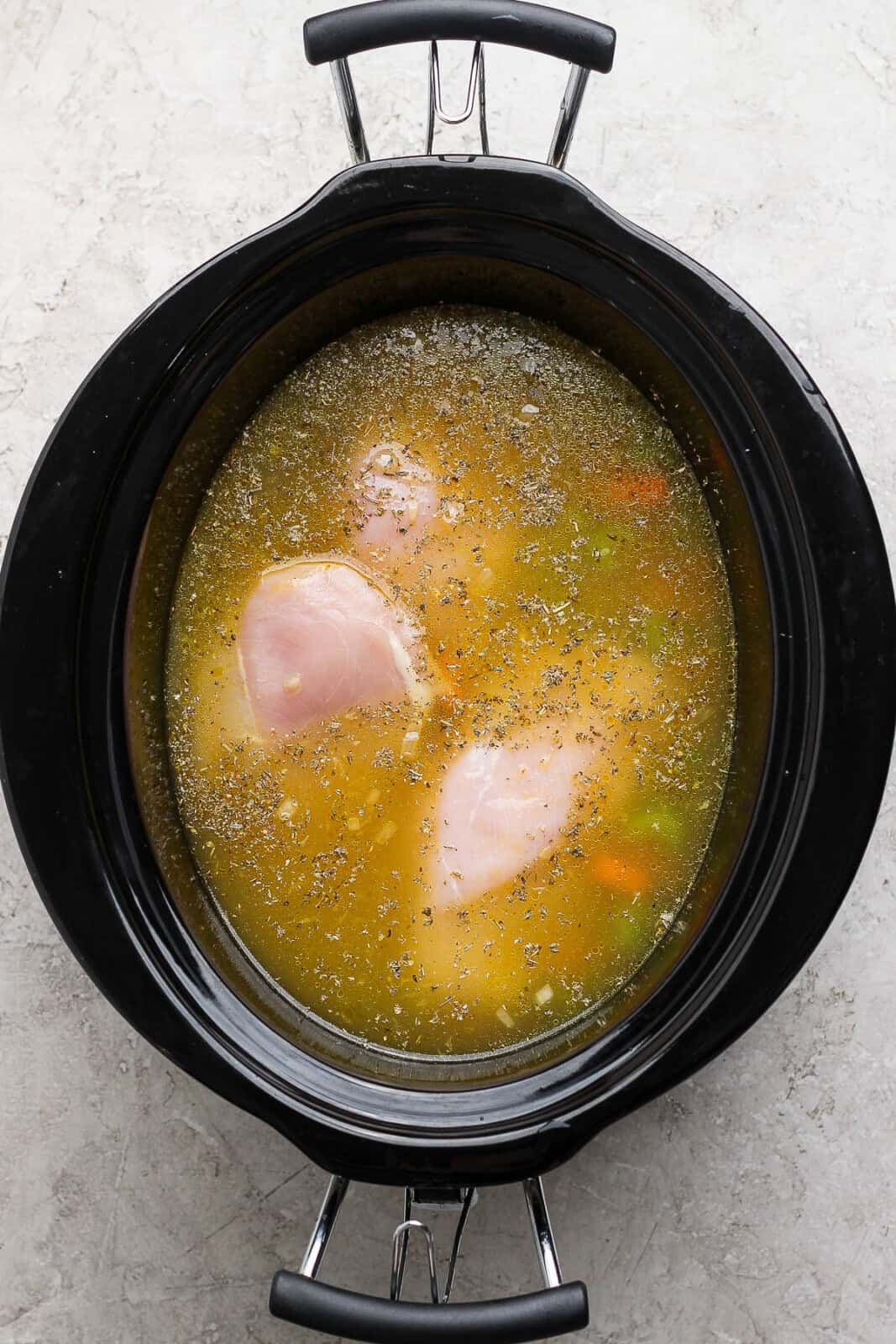 Uncooked slow cooker chicken tortellini soup in slow cooker.