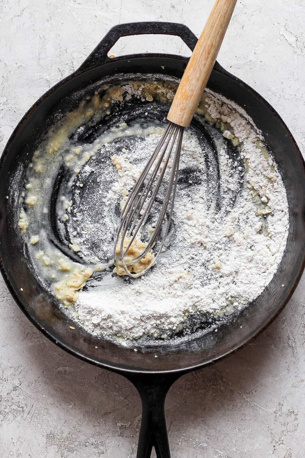 Flour being whisked into melted butter to make sweet potato au gratin.