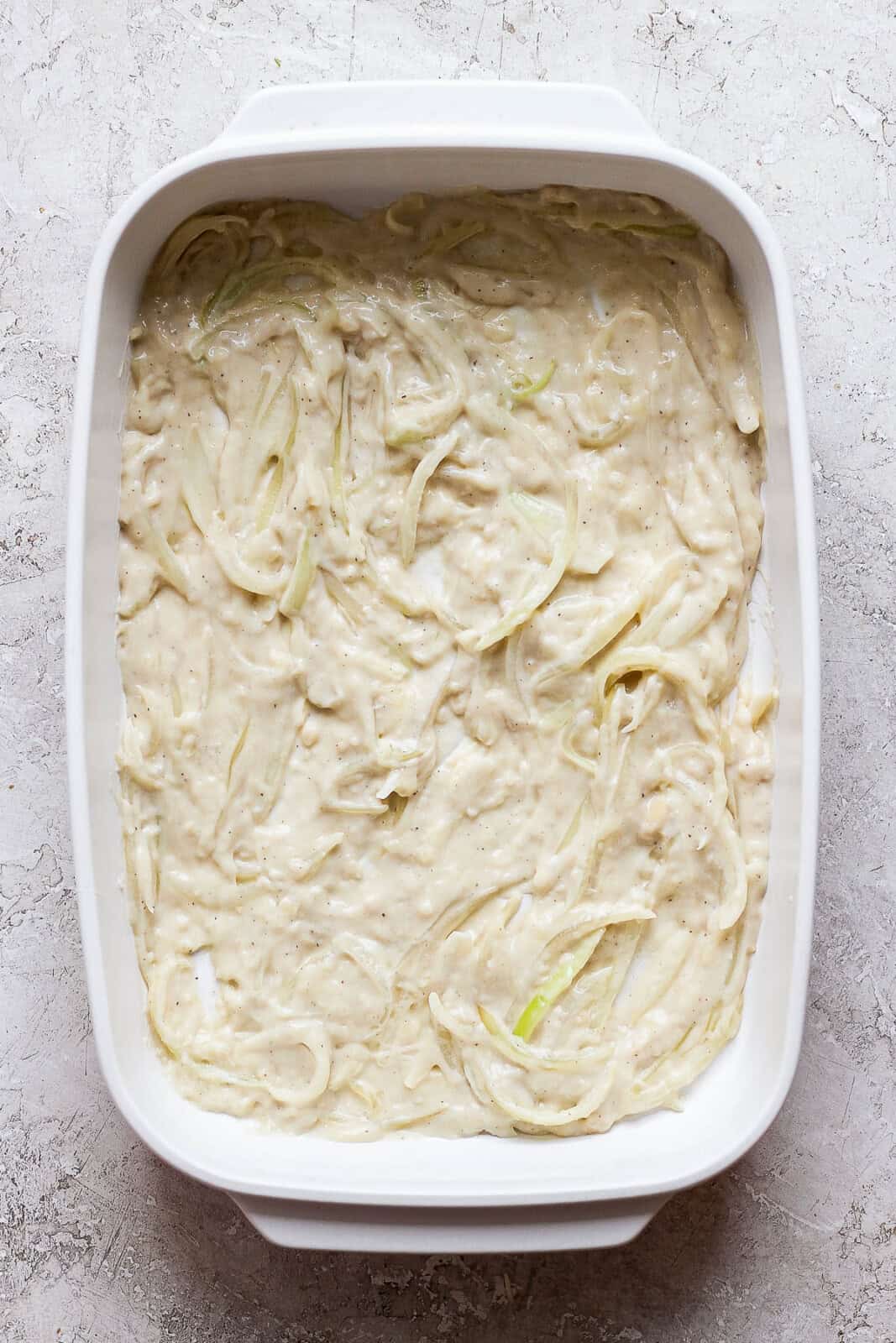 The cheesy cream sauce for sweet potato au gratin spread in the bottom of the pan.