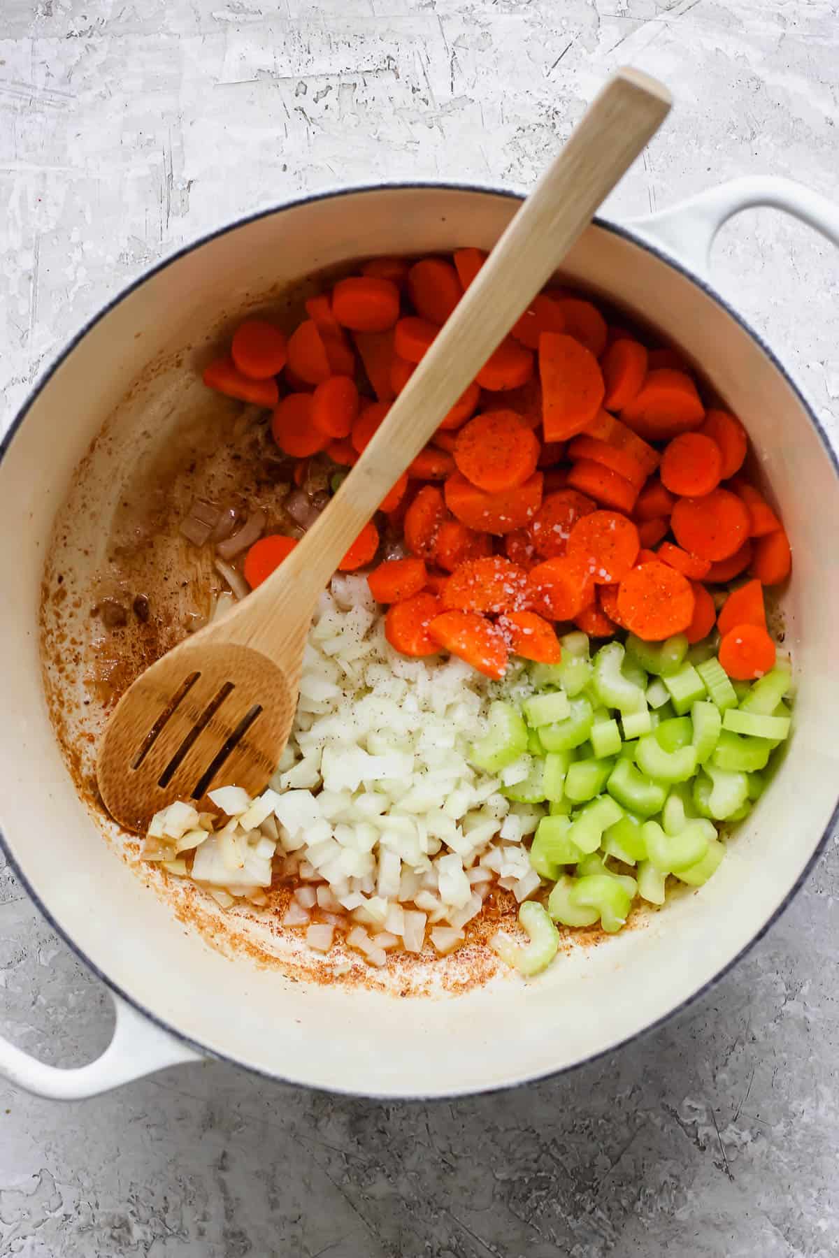 Diced onion, celery, and carrots in dutch oven to make ginger turmeric chicken soup.