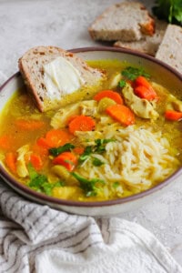 Ginger Turmeric Chicken Soup in a bowl with buttered bread.